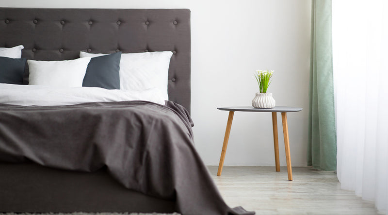Modern bedroom with a bed, side table, and decorative elements.