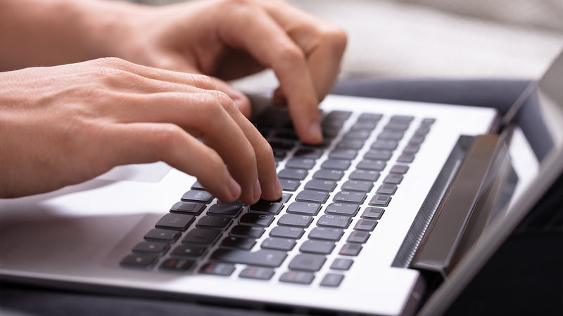 Close-up of hands typing on a laptop keyboard