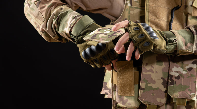 Person wearing camouflage gloves and a jacket on a black background