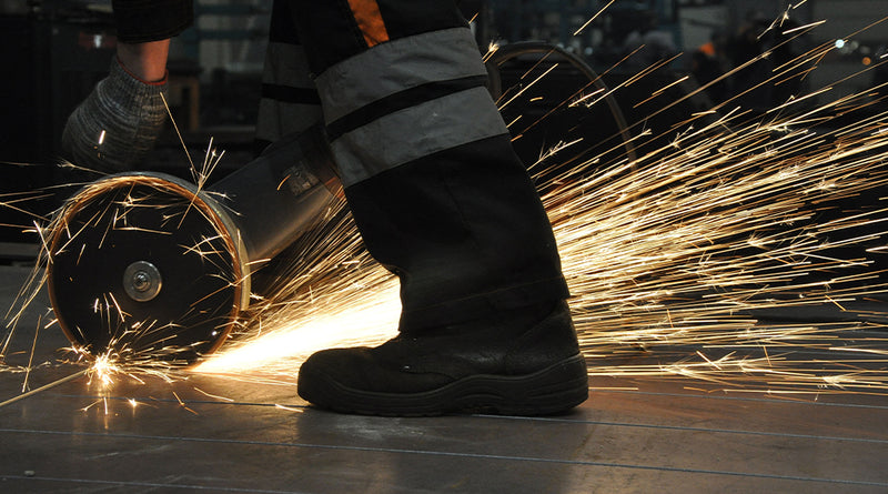 Person using a grinder with sparks flying, wearing protective boots.