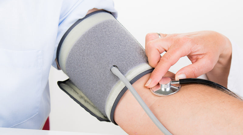 Person having their blood pressure taken with a stethoscope and blood pressure monitor.