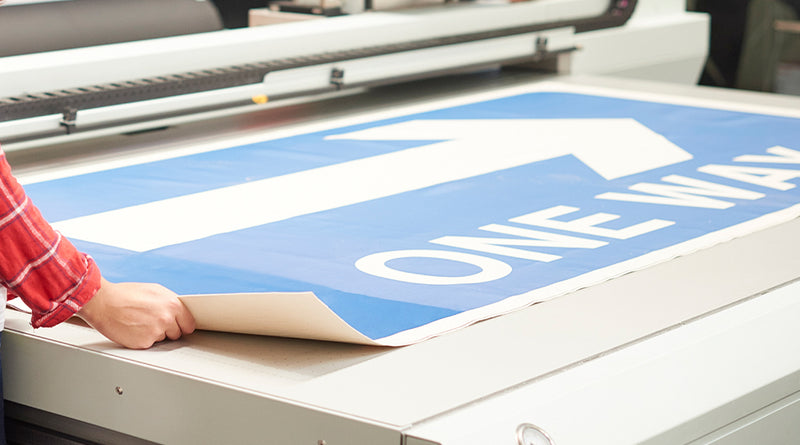 Person working with a one-way sign on a printing machine